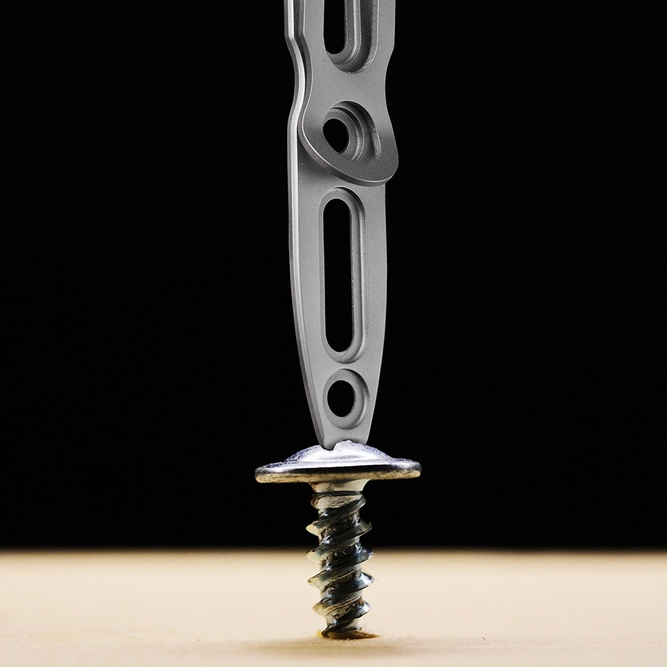 screw screwed into a light wooden block on a dark background